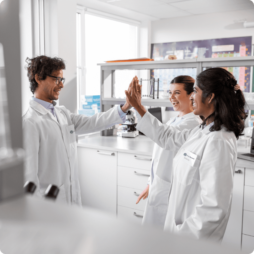 Drei Wissenschaftler in weißen Kitteln arbeiten in einem PhytoSerenity-Labor, analysieren Proben und diskutieren die Ergebnisse.